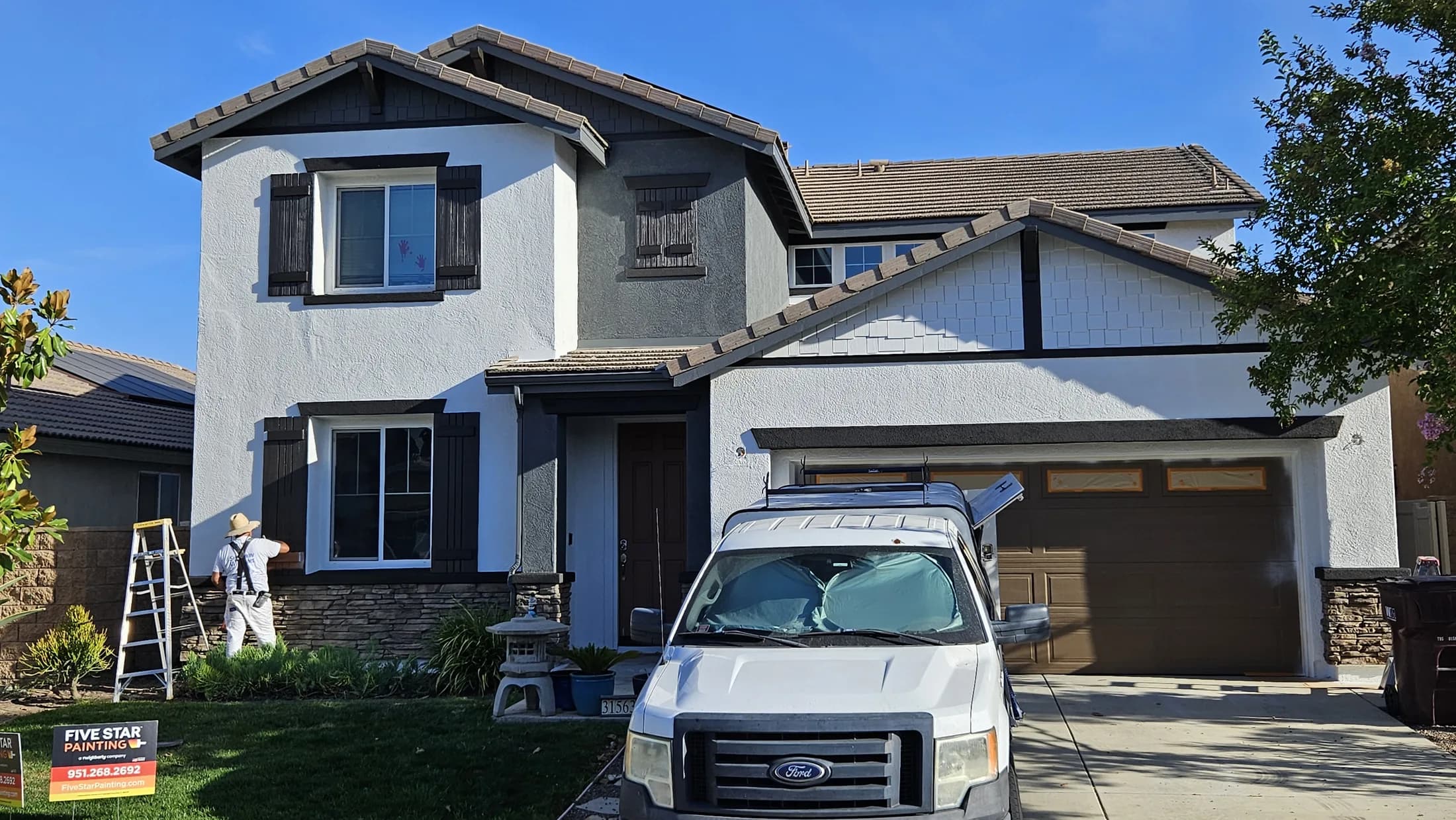 Two-story exterior repaint in progress on a residential project