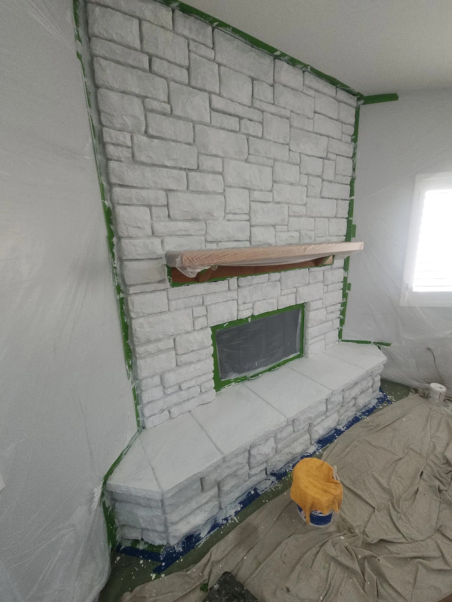 Stone fireplace masked and primed during prep stage